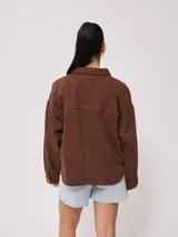 Campera marrón de algodón con cuello camisero, cierre con botones a presión, bolsillos frontales y corte holgado.