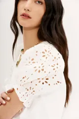 Remera blanca de algodón con calce al cuerpo, cuello redondo y tajos laterales. Mangas balloon con bordado tipo broderie.
