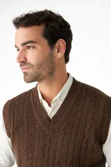 Chaleco de punto color beige con diseño de trenzas, escote en V y sisas amplias.