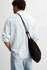 Bolso tipo shopper color marrón oscuro, confeccionado en tejido trenzado de algodón con diseño de macramé. Tiene dos asas de hombro y cierre fruncido en el compartimento principal.