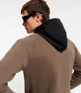 Cardigan de punto color marrón topo, con capucha negra contrastante y cierre frontal de cremallera negra. Presenta bolsillos laterales.