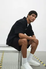 Short cargo negro de popelina de algodón, con cintura elástica ajustable con cordón, bolsillos laterales, bolsillos cargo con solapa y botón a presión en piernas y traseros, y aberturas laterales en el bajo.