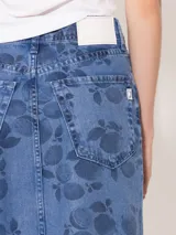 Pollera midi de denim celeste con estampado de limones y hojas en azul oscuro. Tiene corte recto, tiro alto y abertura frontal.