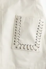 Minifalda color crema de tejido revestido con bolsillos grandes parche adornados con ojales de metal y pespuntes decorativos sobredimensionados. Modelo de tiro alto con cierre oculto y cierre de corchete atrás. Forrada.