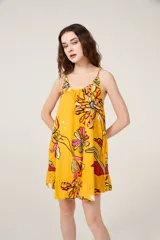 Vestido corto amarillo con estampado de flores, breteles finos y cuello redondo.