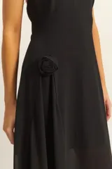 Vestido negro de largo midi, con escote halter y falda asimétrica con caída fluida.