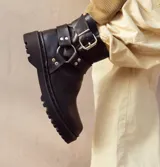 Botas de caña baja color chocolate, realizadas en cuero encerado, con hebillas en la caña y herrajes de níquel. El fondo es de suela negra realizado artesanalmente y el interior está forrado en forrería vacuna.