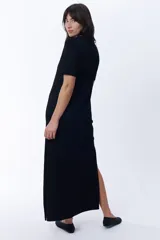 Vestido largo negro de corte recto con cuello redondo y mangas cortas. Presenta aberturas laterales en el ruedo.