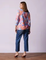 Blusa de algodón con estampado de flores en tonos rosa, naranja, azul y blanco. Tiene cuello cuadrado con borde celeste y mangas 3/4 con borde celeste.