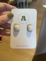 Par de aros Aitana con forma rectangular, color crema con borde dorado y detalle de strass.