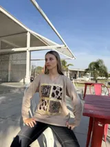 Remera roja de manga larga con cuello en V y estampado frontal con recuadros de animal print en dorado.