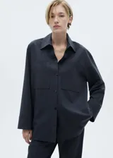 Camisa azul marino a rayas diplomáticas, de corte recto, con cuello camisero, cierre frontal con botones y dos bolsillos de parche en la parte delantera.