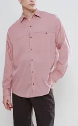 Camisa manga larga color rosa, de calce oversize, con bolsillo con ojal y botón en el delantero.