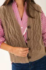 Chaleco de punto color rojo con diseño trenzado, escote en V y cierre frontal con botones.