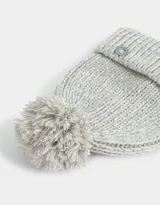 Gorro de lana tejido color rosa viejo, con pompón en la parte superior y etiqueta metálica con logo en el borde.