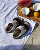 Sandalias bajas de cuero color tostado y beige, con doble tira ancha y plantilla de cuero.