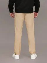 Pantalón chino color beige confeccionado en sarga de algodón elástica suave, de corte regular y pierna estrecha en el tobillo.