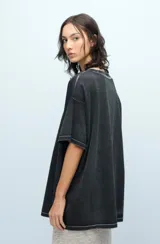 Remera negra de jersey de algodón peruano, con calce oversize, escote a la base y mangas cortas. Presenta un estampado de gatos y la palabra 'Ginebra' en el frente.