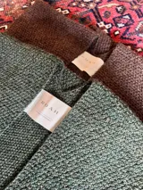 Ruana de tejido de punto color verde inglés, confeccionada en 100% baby alpaca.