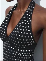 Top negro con cuello halter y apliques de tachas plateadas.