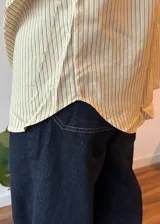 Camisa color crema a rayas verticales finas, de corte oversize y manga larga.