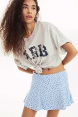 Short pollera mini de tejido suave con efecto neopreno, color celeste con estampado floral en azul oscuro. Modelo ajustado con elástico oculto en la cintura y nesgas que aportan volumen.