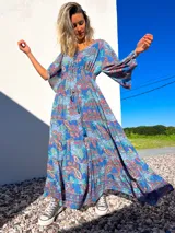 Vestido túnica largo de algodón con estampado de arabescos en tonos azules, rojos y verdes. Tiene escote en V con cordones y mangas acampanadas.