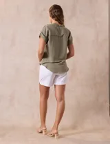 Camisa verde oliva de manga corta con cuello con solapa y abertura central con botones. Tiene un bolsillo aplicado en el pecho.