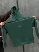 Canguro verde con capucha ajustable con cordones, bolsillo tipo canguro y logo pequeño estampado en el pecho.