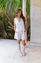 Conjunto de dos piezas color rojo vibrante, compuesto por un chaleco sin mangas con escote en V y botones frontales, y un short de tiro alto con pliegues y bolsillos laterales.