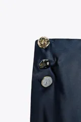 Falda midi azul marino de satén con cintura elástica y detalle de botones dorados en el lateral.