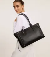 Cartera satchel grande color negro, confeccionada en material sintético con cierre de cremallera, detalles de spikes y asa larga.