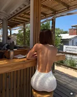 Vestido largo de tejido de punto blanco marfil, con escote halter anudado y aberturas pronunciadas en los laterales de la cintura. Presenta un tajo en la falda.