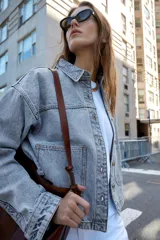 Cazadora de denim verde oliva, con cuello solapa, manga larga, bolsillos delanteros de plastrón y cierre frontal con botones metálicos.