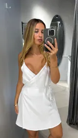 Minivestido blanco con breteles finos y corte cruzado con lazo en la cintura.