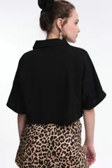 Camisa corta color crudo con textura arrugada, corte crop, cuello camisero, cierre frontal con botones y mangas cortas con puños.