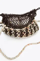 Bolso mini de hombro trenzado con combinación de colores y materiales en el cuerpo. Asa de hombro y bolsa interior de mesh con cierre fruncido.