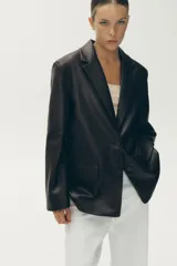 Blazer marrón oscuro de efecto piel, con cuello solapa y manga larga. Tiene bolsillos de plastrón en la parte delantera, forro interior a tono y cierre frontal con botones.