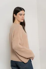 Sweater beige de tejido bouclé, con cuello redondo y mangas largas.