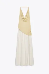 Vestido largo de fiesta con cuello halter fluido y hombros descubiertos. Presenta un top dorado drapeado y una falda larga color crema con textura.