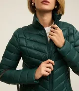 Campera puffer ultraligera color marrón, confeccionada en poliamida acolchada, con cuello alto y cierre por cremallera. Incluye bolsita con cordón.