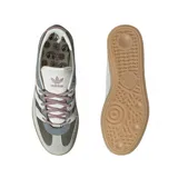 Zapatillas Adidas Handball Spezial ST en tonos gris, verde oliva y blanco. Confeccionadas en gamuza y material textil, con las tres tiras laterales en blanco y suela de goma color caramelo.