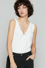 Blusa sin mangas blanca, con botones frontales y un diseño de bolsillo.