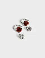 Set de dos pares de aros plateados: un par de argollas con dije de rosa roja y un par de aros tipo botón con forma de moño.