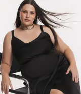 Vestido midi de tela satinada color negro, con escote drapeado, breteles medianos, cintura ajustada y pollera cruzada.