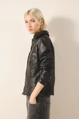 Camisa de cuero ovino color negro, de corte jeanero, con bolsillos tipo ojal en el delantero y cierre frontal con broches a presión con el logo de Rapsodia.