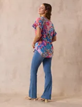 Blusa estampada con motivos florales en tonos rosa, azul y naranja. Tiene cuello en V y mangas cortas con volados.