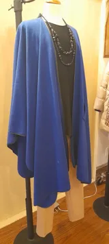 Ruana larga azul royal de paño con presilla y vivo negro en el borde.