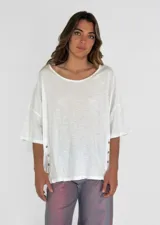 Remera color amarillo con cuello redondo y mangas cortas amplias, con detalle de botones en los laterales.