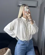 Camisa blanca de mangas largas con detalles de encaje en el cuello y en el frente.